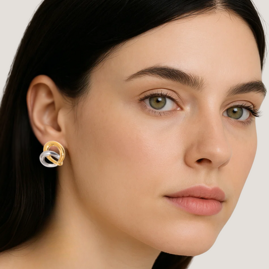 model wearing heart-shaped earrings with interwoven gold and silver tones. 